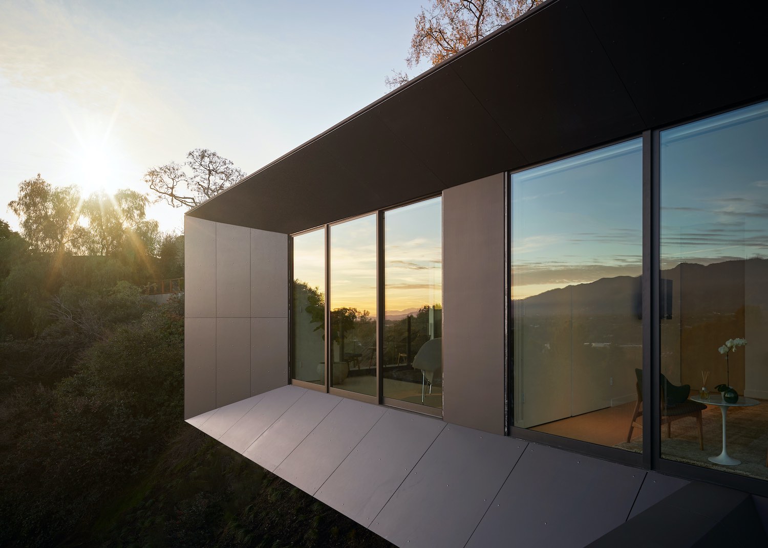 reflection of the sunset and trees on the window of the house 