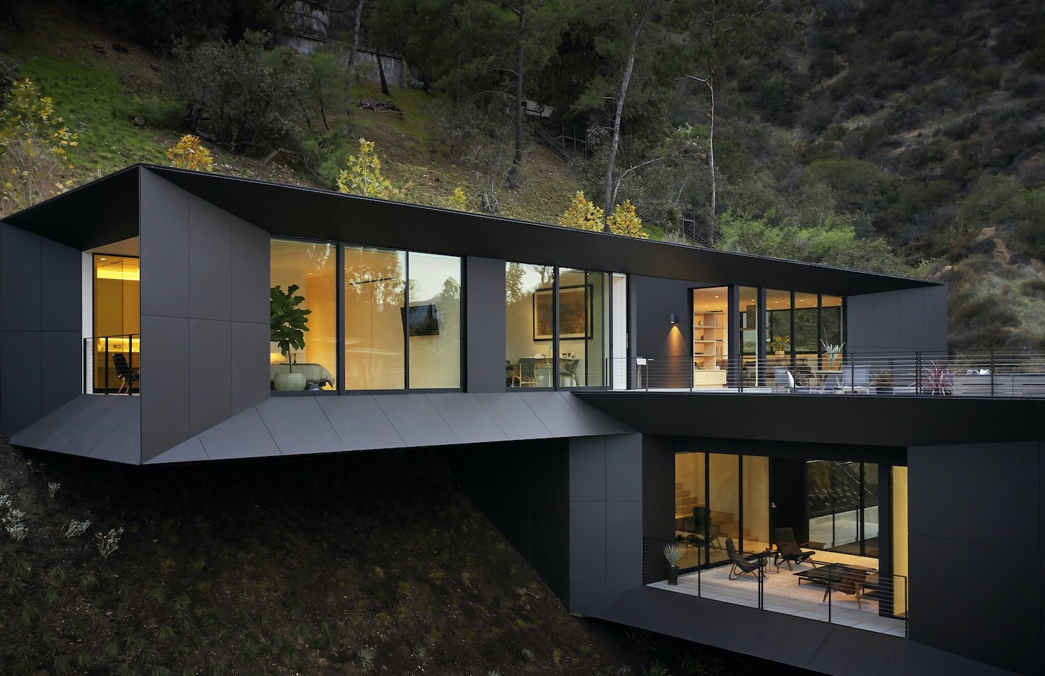 black modern house on a hill surrounded by trees 